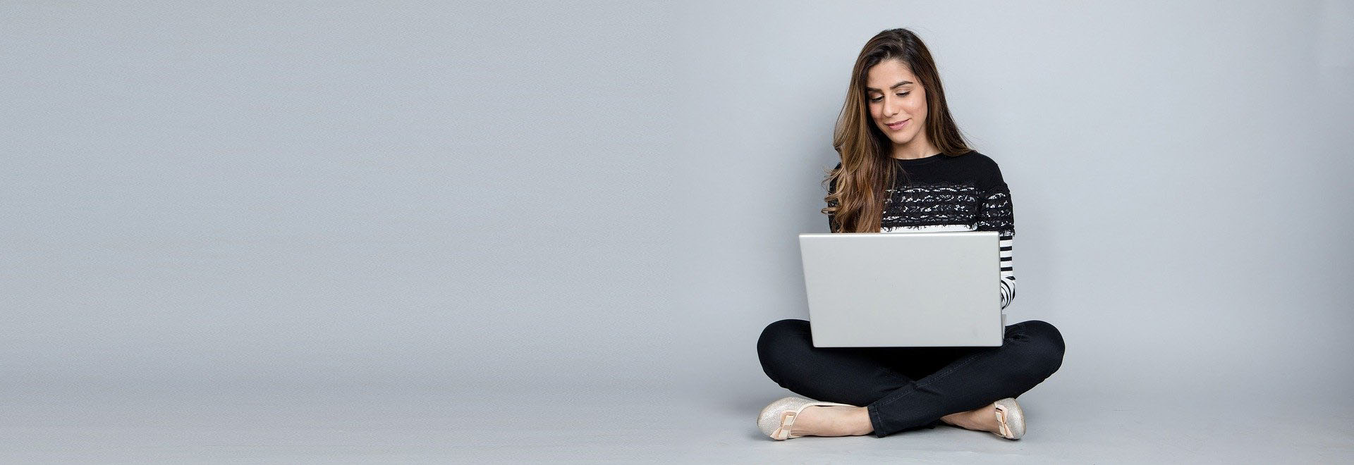 junge Frau im Schneidersitz mit Laptop