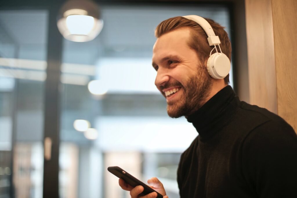 Lächelnde Person mit Kopfhörern und Smartphone